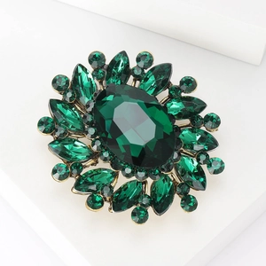 Macro shot of vintage gold floral brooch with large oval green gemstone and crystal detail