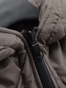 Detail shot of black matte metal zipper and fine quilted fabric on a brown parka