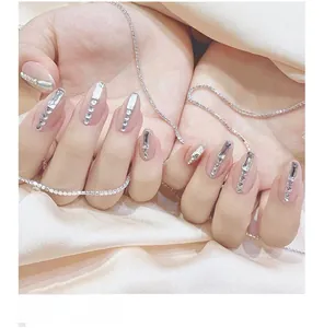 Detailed close-up of nude pink press-on nails with vertical rhinestone and zircon accents