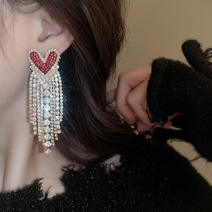Macro detail of Ancora red heart tassel earrings with sparkling rhinestones on model