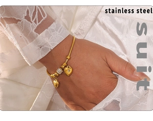 Detailansicht eines goldenen Edelstahl-Schlangenarmbands mit Herzanhängern und weißen Strasssteinen
