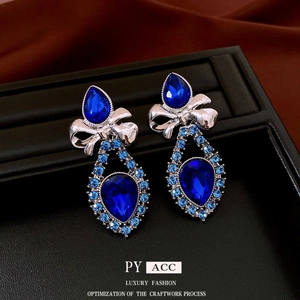 Blue water drop crystal necklace and earrings set with silver bow design on black tray