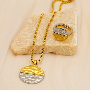 Hammered two-tone gold and silver stainless steel necklace and ring jewelry set on stone