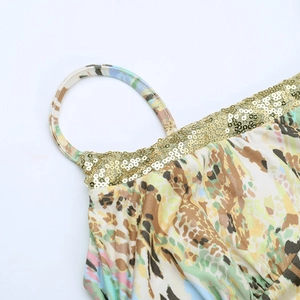Detailed close-up of golden sequins and abstract leopard print on a beach sundress