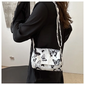 White crossbody bag with butterfly prints shown on a model for size and style reference