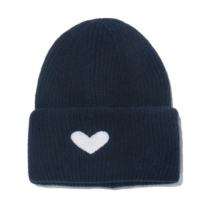 Close-up of dark blue ribbed knit beanie featuring a white embroidered heart pattern