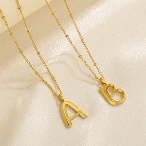 Close-up of golden 3D initial A and B pendants on a delicate satellite chain necklace