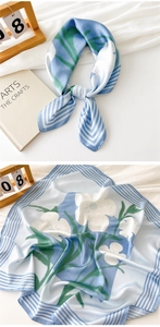 Close-up of sky blue satin square scarf with white floral patterns and striped borders