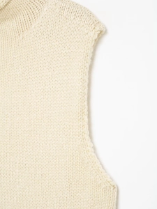 Close-up of cream white chunky knit asymmetrical vest showing soft texture and weaving