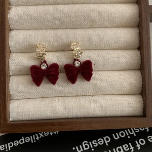Détail de boucles d'oreilles nœud en velours rouge avec cristaux de zircon scintillants