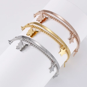 Detail of layered snake chain bracelets with butterfly and star charms in three colors