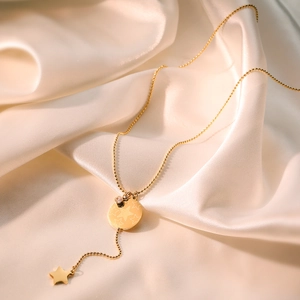 Minimalist gold plated star pendant necklace on cream silk background for a luxury look