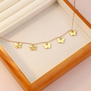 Elegant gold butterfly necklace with five pendants displayed in a wooden jewelry box