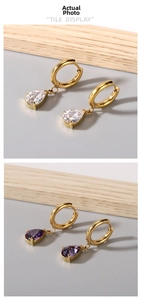 Close-up of teardrop zircon pendants on gold hoop earrings in white and purple colors