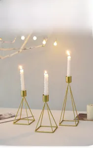 Detailed view of three gold geometric metal candle holders in varied heights for decor