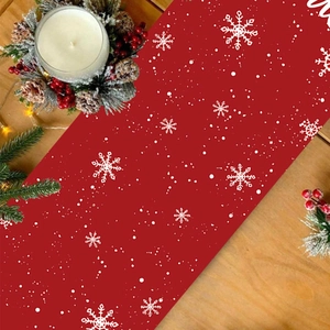 Red Christmas table runner with white snowflake patterns on a festive wooden table set