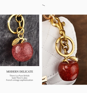 Sparkling red apple keychain with gold hardware displayed as a stylish bag accessory