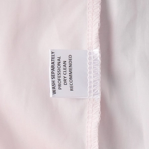 Macro view showing washing care labels on cotton trousers with fabric texture details