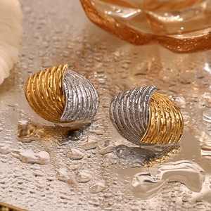 Macro detail of gold and silver spiral earrings with textures on a reflective surface