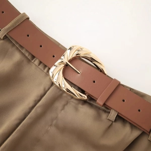 Ceinture femme marron avec boucle dorée ondulée sur un pantalon kaki