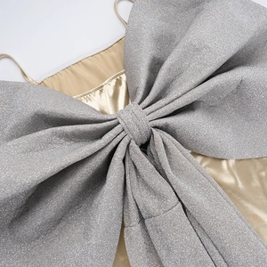 Détail macro du nœud argenté scintillant et du tissu en satin champagne de la robe