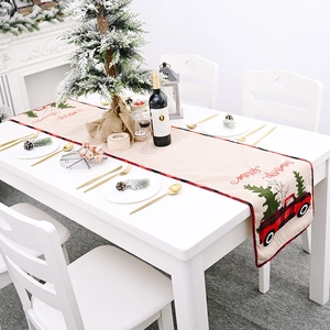 Beige Christmas table runner with red truck and tree patterns in cozy dining setting