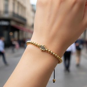 Detailed view of copper gold-plated bracelet with blue diamond Hamsa hand on wrist