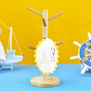 Cute plush durian keychain hanging on a wooden display stand with nautical background