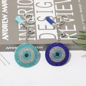 Evil Eye rhinestone keychains with tassels and bells on modern book background