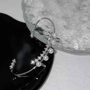 Macro detail of silver ear cuff with white pearls and sparkling cubic zirconia stones
