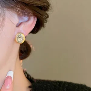 Elegant gold oval stud earrings with crystal halo and matte finish worn by model