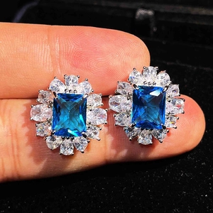 Close-up of rectangular blue gemstone earrings surrounded by white pear-cut crystals