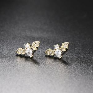 Gold bat stud earrings featuring a teardrop zircon and pavé crystals on a black display