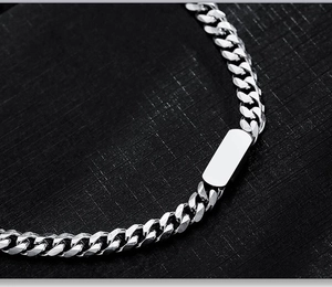 Detailed close-up of a polished silver titanium steel cuban link bracelet with a blank bar