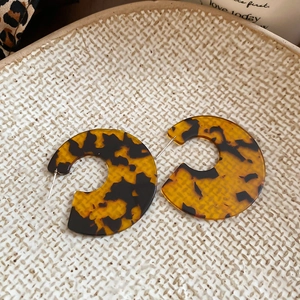 Detail view of tortoiseshell acrylic C-shape earrings on a textured ceramic tray
