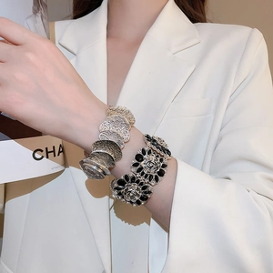 Close-up of diamond-studded black rose bracelet and textured silver cuff bangle