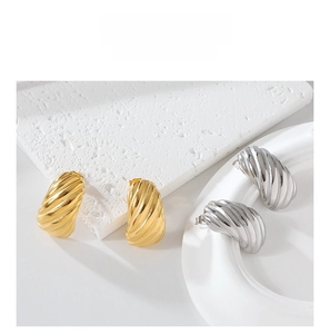 Macro detail of gold and silver croissant earrings with premium textured stripe finish