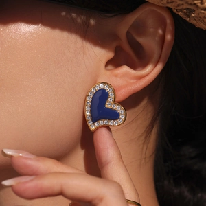 Elegant gold heart earrings with blue enamel and crystal halo shown on model