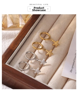 Detailed shot of gold and silver starfish hoop earrings on beige velvet display