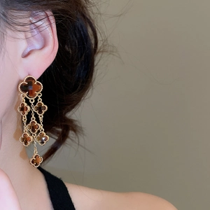 Detail of amber clover tassel earrings with gold plating on model showing elegant drape