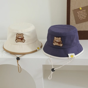 Detail of baby sun hat with cute bear patch, canvas texture, and adjustable chin strap