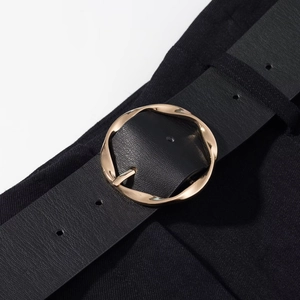 Close-up of black leather belt with twisted texture golden metal round buckle for women