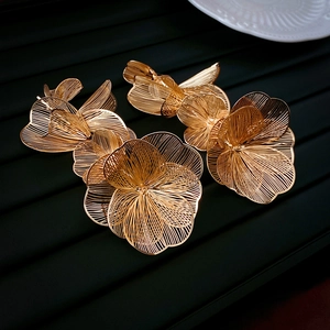 Macro detail of gold flower earrings featuring hollow textured petals and metallic finish