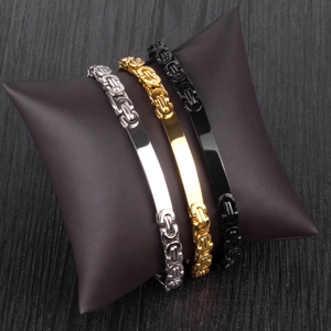 Flat paperclip chain bracelets in gold, silver, and black finish on a leather display