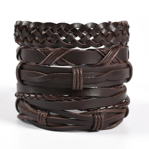 Detail of stacked multi-layer brown leather and rope braided bracelets on white backdrop