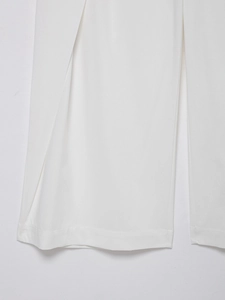 Detail of white linen trousers hemline showing precise stitching and woven texture