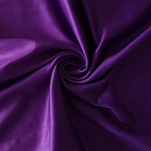 Detailed macro view of glossy purple satin fabric with elegant drapery and fine texture