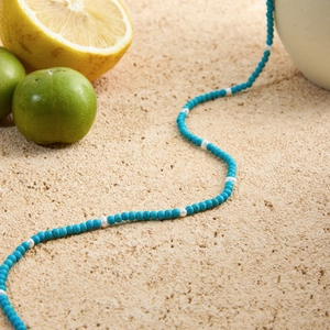 Detail of beaded necklace with blue turquoise beads and white pearls on stone surface