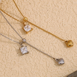 Detail of square zircon necklaces with heart tassels in gold and silver finish
