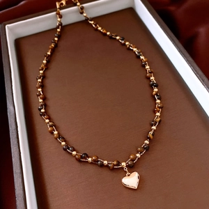 Macro shot of a golden heart pendant on a brown tiger eye beaded necklace in a gift box